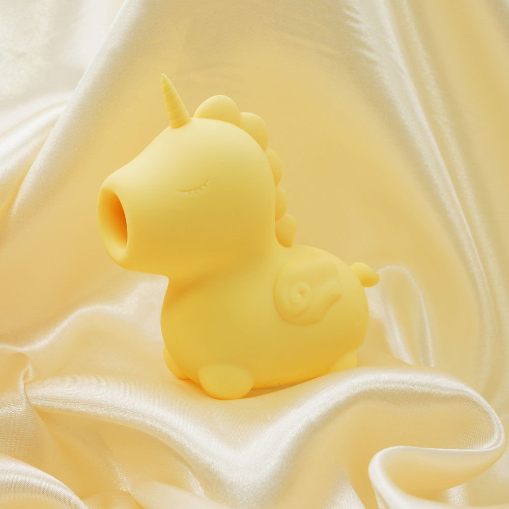Side view of the yellow Unihorn Bean Blossom clitoral stimulator resting on soft yellow satin fabric, with the clitoral stimulation tip prominently displayed | Flirty bay adult store and lingerie